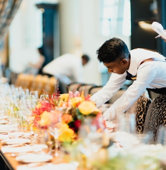 man in white top standing next to table