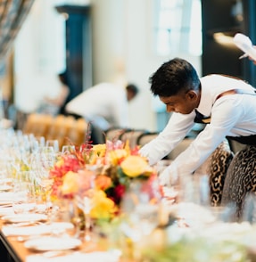 man in white top standing next to table