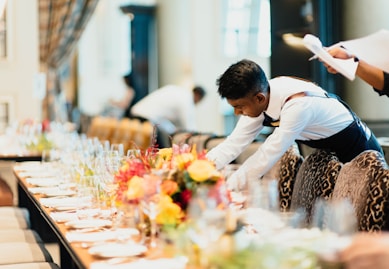 man in white top standing next to table