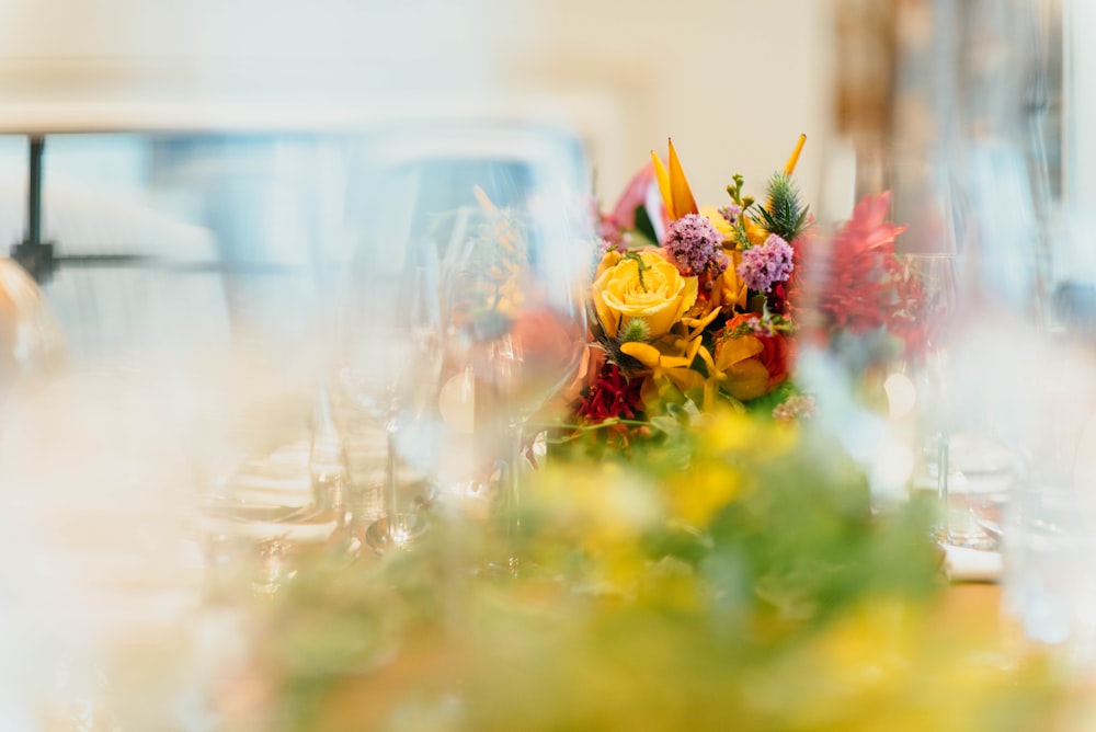 tilt shift lens photography of yellow flower near wine glass