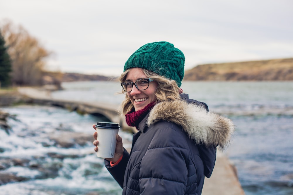 woman in black coat holding cup