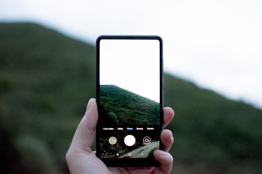 스마트폰으로 산의 사진을 보여주는 사람