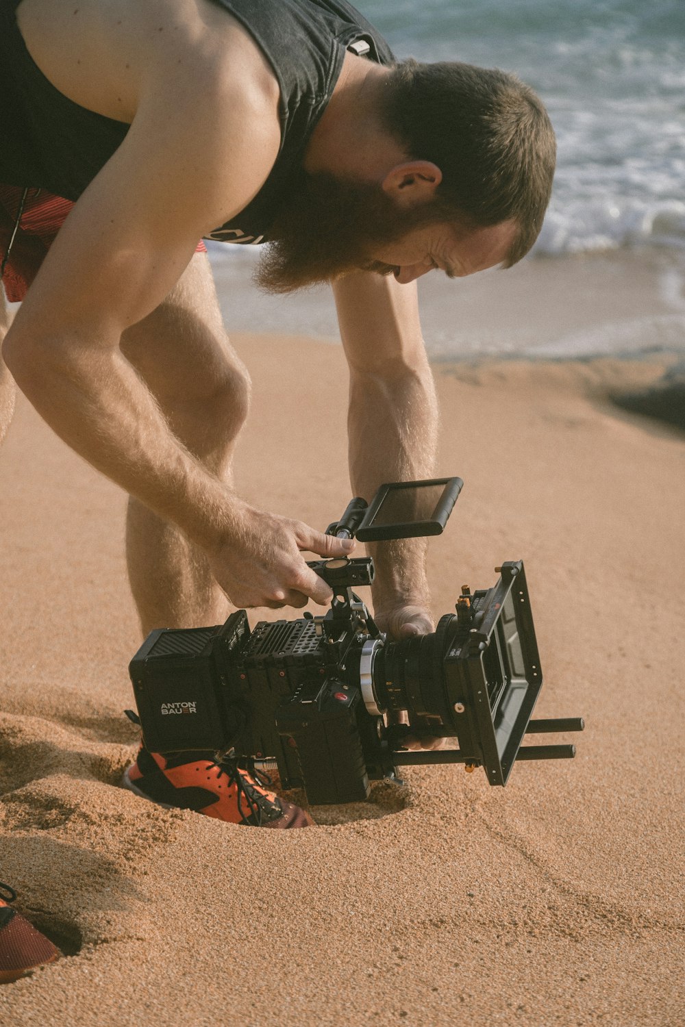 man holding film recorder near seashore