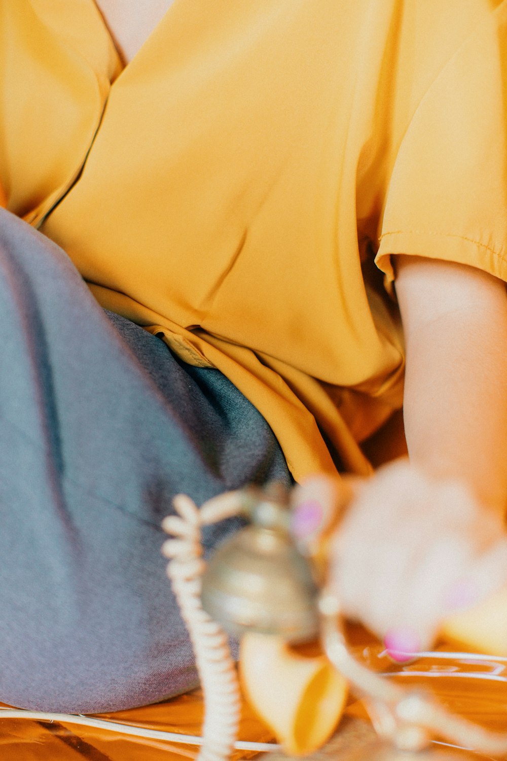 person wearing yellow shirt holding telephone