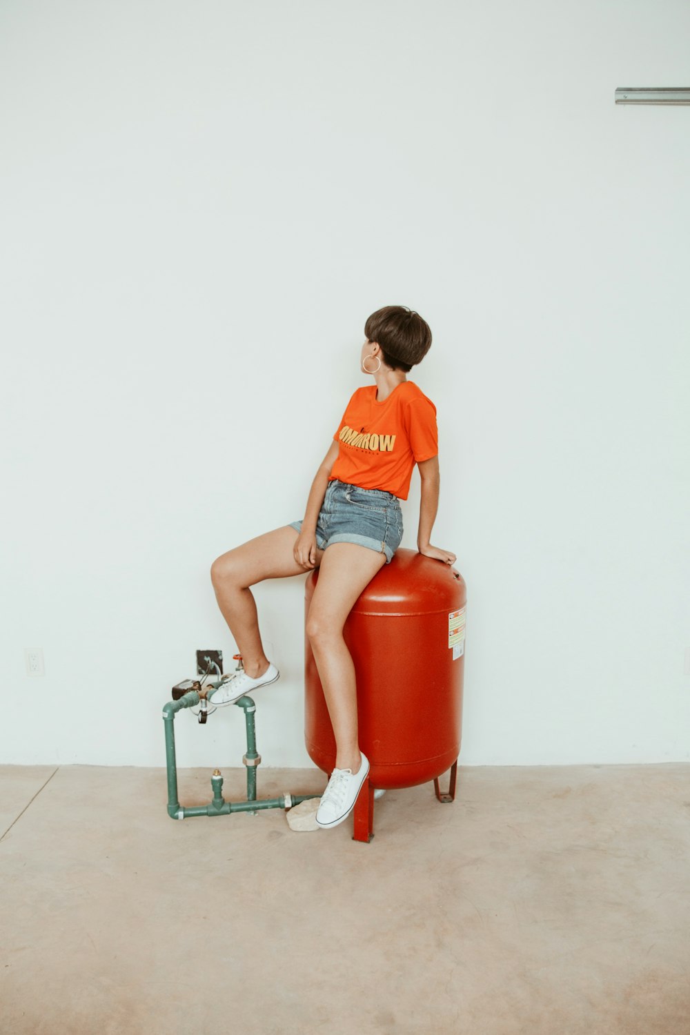 Mujer sentada en tanque de metal rojo