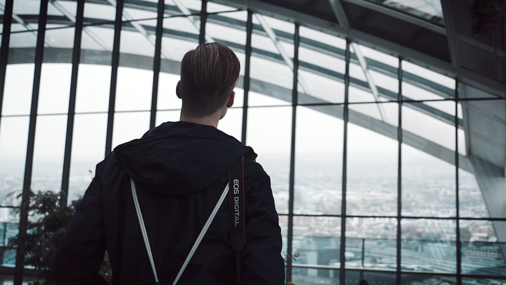 man looking at glass building