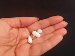 person holding four assorted medicine tablets