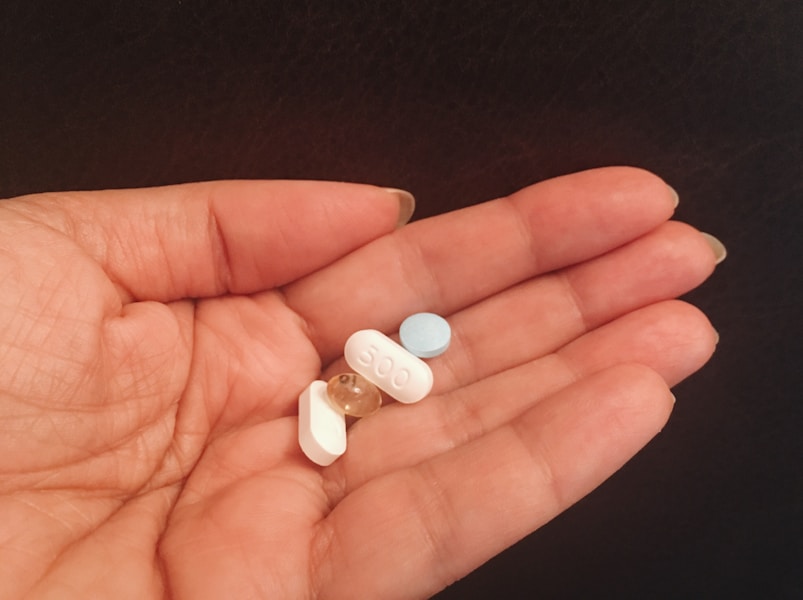 person holding four assorted medicine tablets