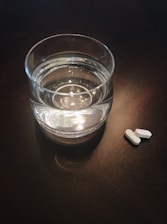 Close-up of a hand dissolving a Nuroclean tablet in a glass of water on a kitchen counter.