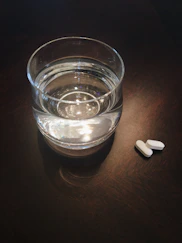A peaceful morning scene with a glass of water and supplements on a bedside table.