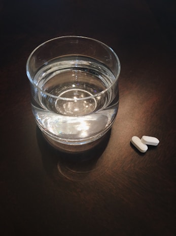 Ozemfit capsules placed next to a glass of water on a kitchen counter bathed in morning light.