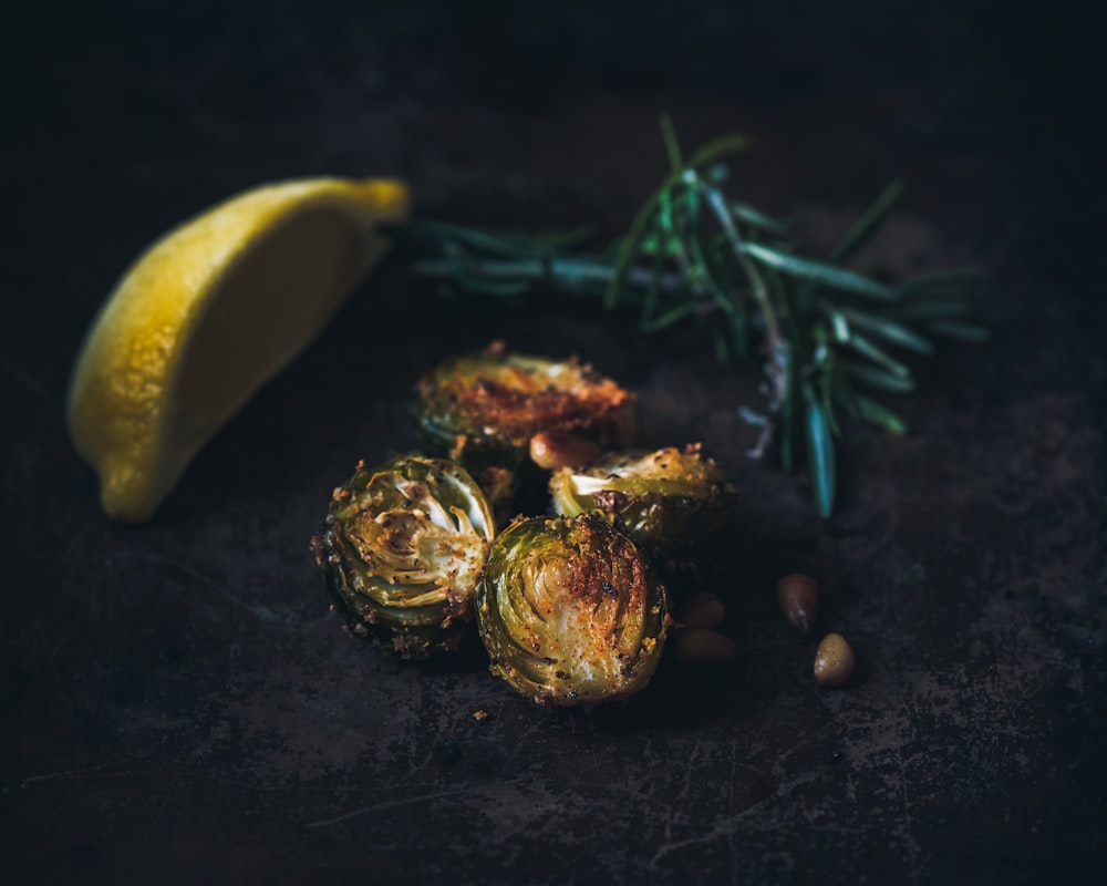 selective focus photography of grilled Brussels sprout, lemon wedge, and rosemary sprig