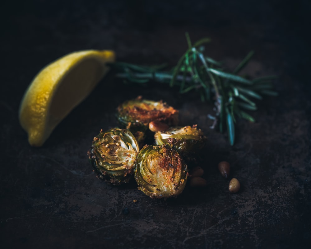 selektive Fokusfotografie von gegrilltem Rosenkohl, Zitronenspalte und Rosmarinzweig