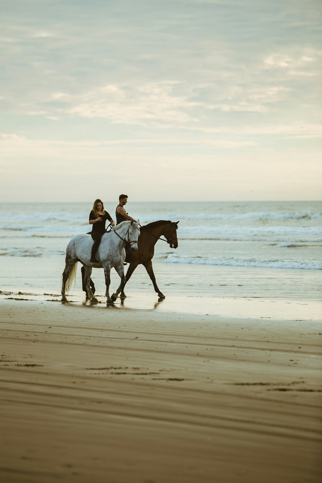 man and woman riding on horse near seashore