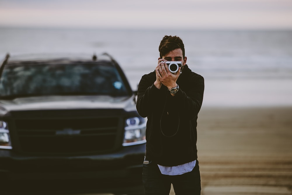 a man taking a picture of a truck on the beach
