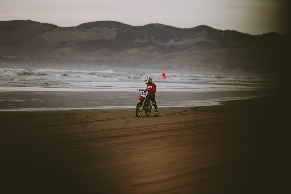 hombre montando motocross dirt bike cerca de la orilla del mar