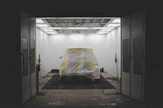 Front view of a sleek car being professionally spray painted in a modern workshop.
