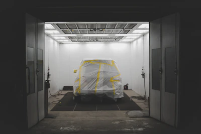 Close-up of a car door being carefully wrapped with protective film in a modern workshop
