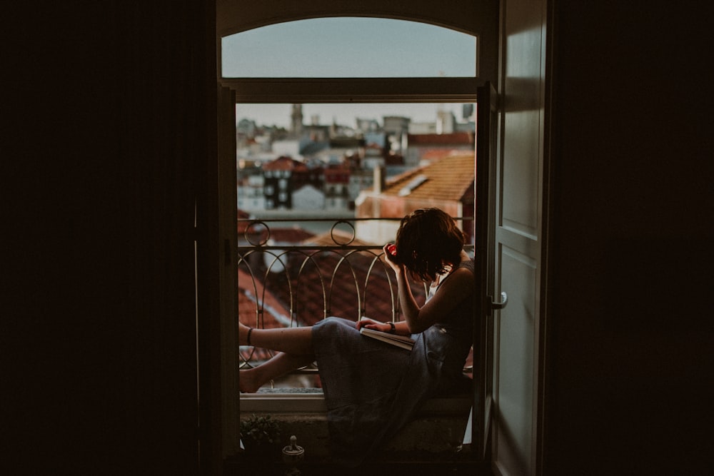 woman wearing gray dress sitting near window during daytime