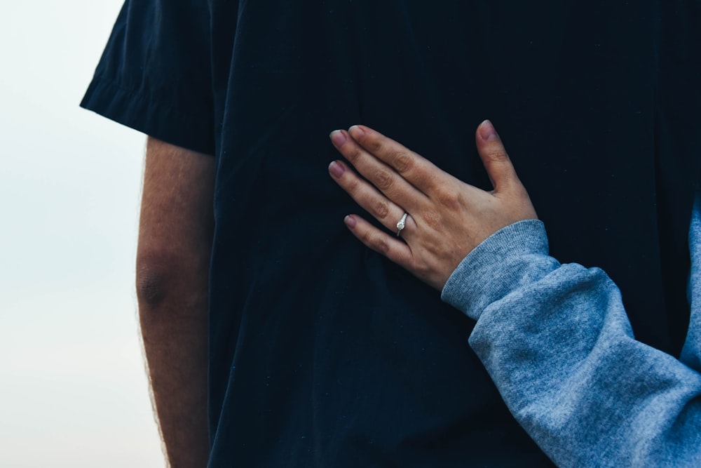 person wearing blue long-sleeved shirt resting its hand on man wearing black shirt