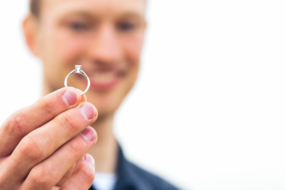 person holding silver-colored clear gemstone encrusted ring