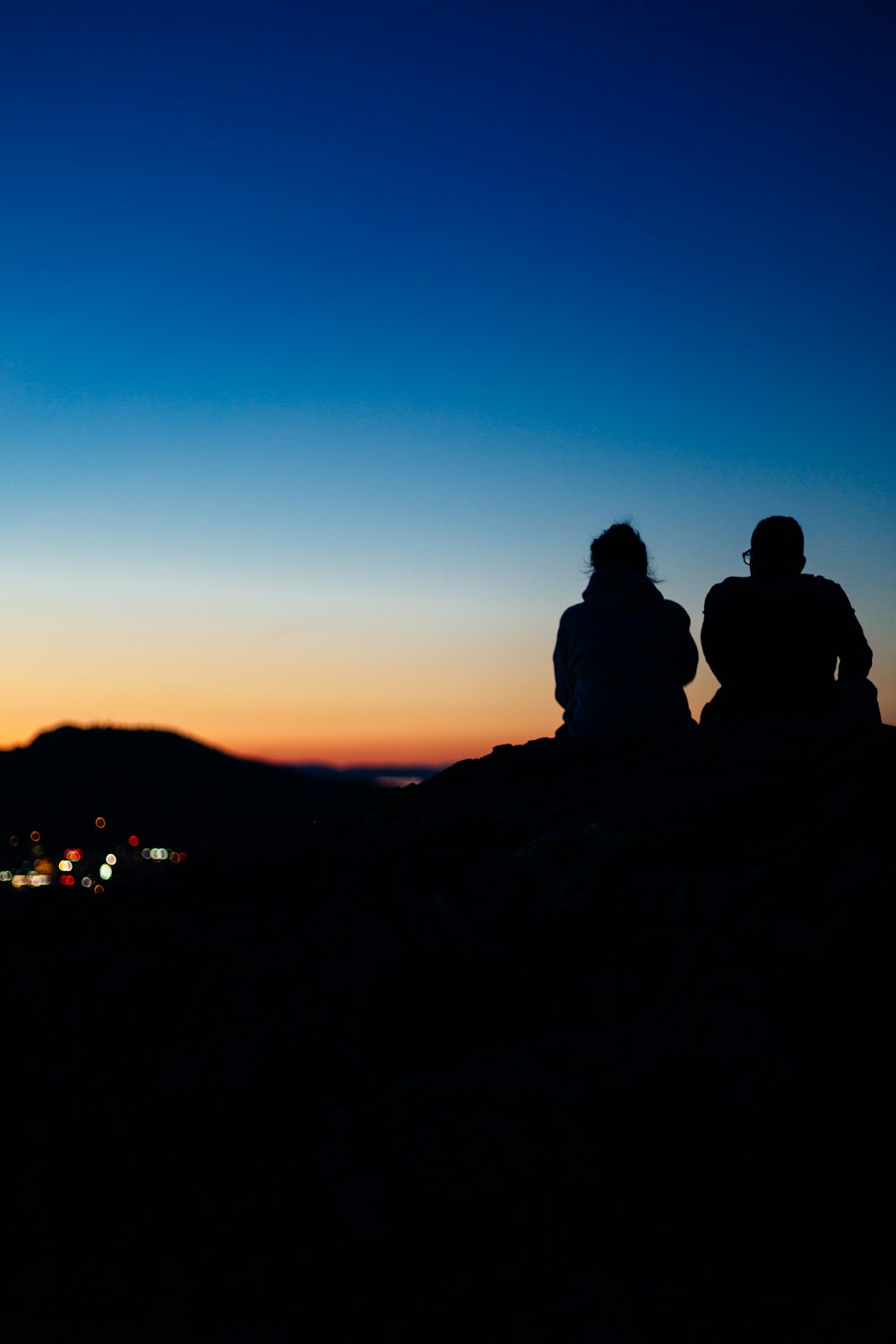 Dos personas de la silueta sentadas durante la puesta del sol