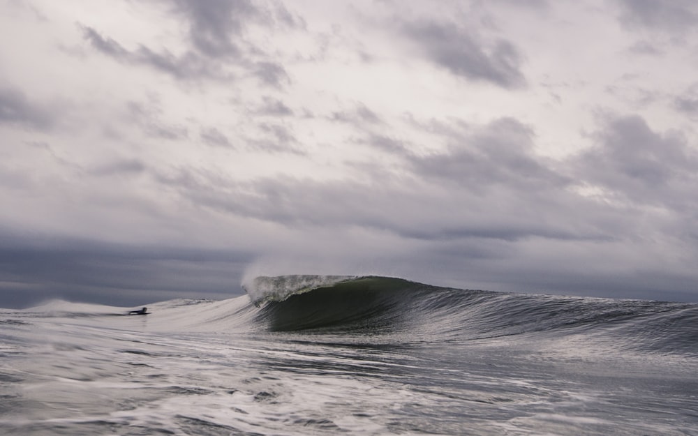 surfer on body of water in front of waves at daytime