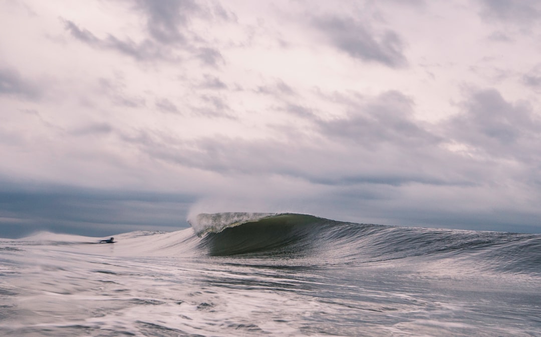 surfer on body of water in front of waves at daytime