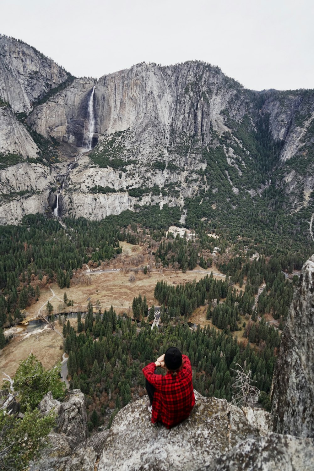 man sitting on cliff during daytime