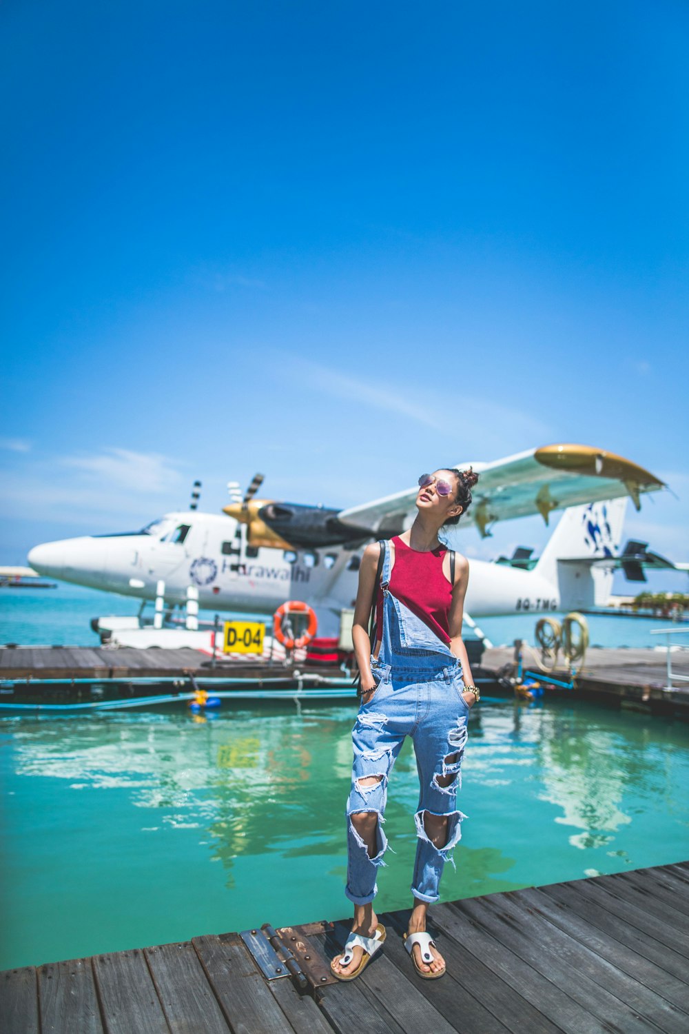 woman standing on grey wooden dock looking up