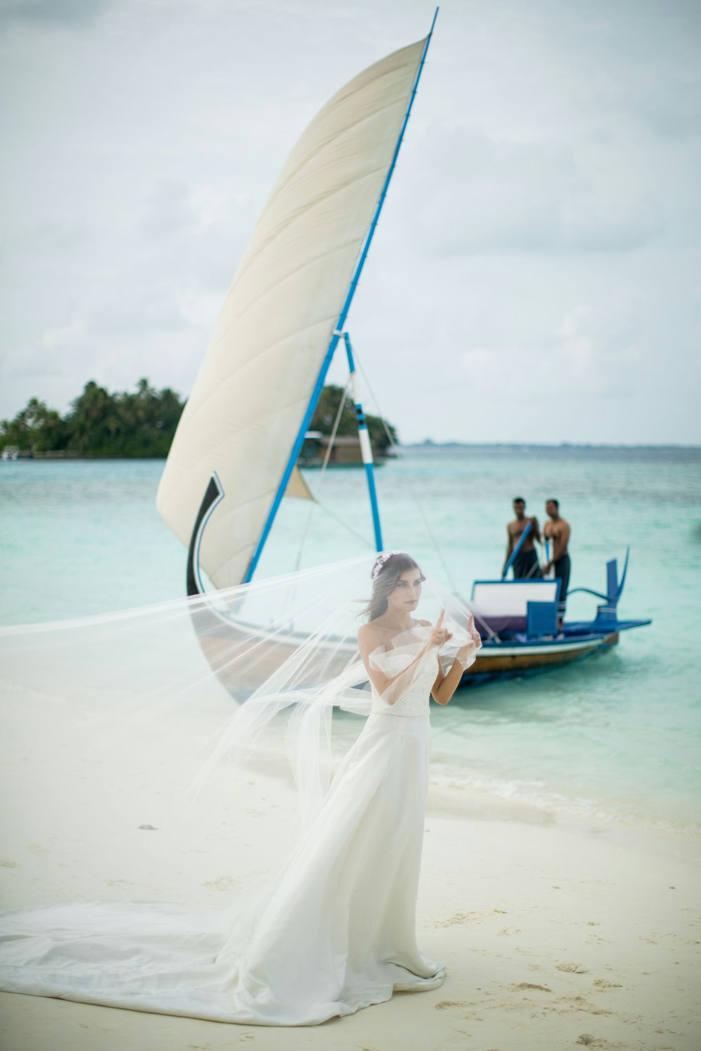 Frau in weißem Hochzeitskleid mit Schleier geht am Ufer spazieren