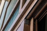 A close-up view of a partly open sliding door with a wooden frame and metal hardware. The door showcases smooth lines and a modern design, with visible elements like the track and locking mechanism.