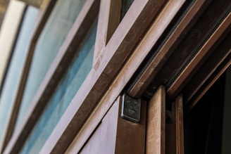 A close-up view of a partly open sliding door with a wooden frame and metal hardware. The door showcases smooth lines and a modern design, with visible elements like the track and locking mechanism.