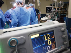 Close-up of a neurophysiologist monitoring brain signals during surgery in a high-tech operating room.