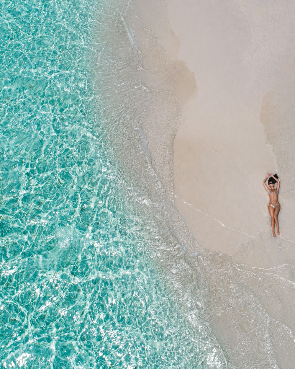 Mulher deitada na areia marrom durante o dia