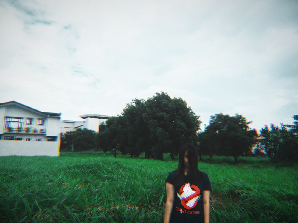 woman standing on green field near white building