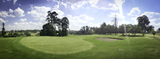 A sunlit view of the lush green fairways winding through mature trees at Pavenham Park Golf Club.