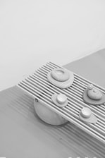 Close-up of hands delicately arranging minimalist design elements on a matte black surface.