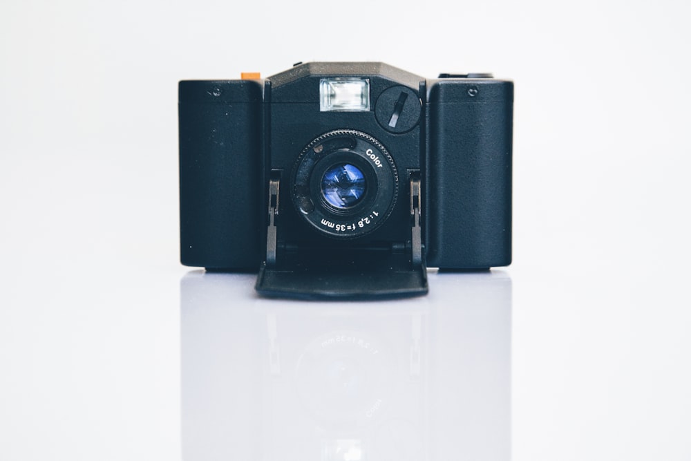 Fotocamera nera su pannello bianco