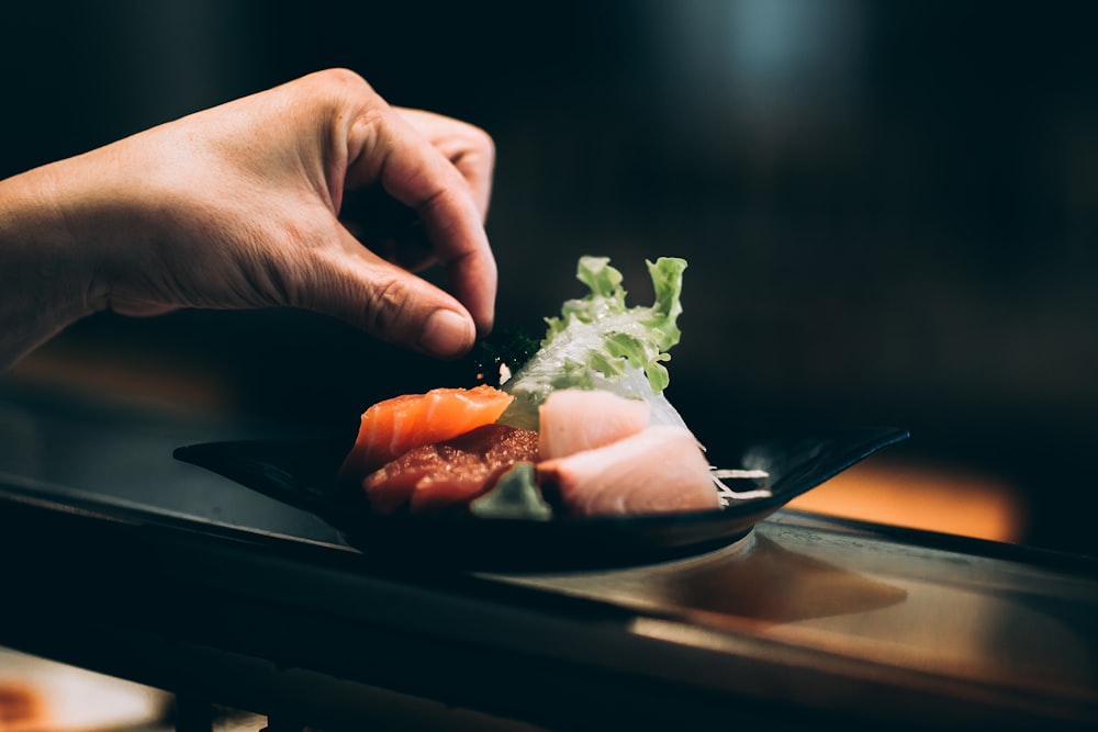 left hand picking vegetable on plate