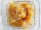 A close-up view of fresh honeycomb in a square glass container, with golden honey oozing from the hexagonal wax cells.