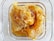 A close-up view of fresh honeycomb in a square glass container, with golden honey oozing from the hexagonal wax cells.