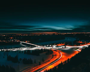 A sleek aerial shot of an illuminated highway interchange at dusk, symbolizing dynamic connectivity and fluid motion.