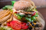 hamburger with vegetables and meat beside French fries
