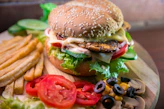 hamburger with vegetables and meat beside French fries
