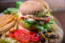 hamburger with vegetables and meat beside French fries