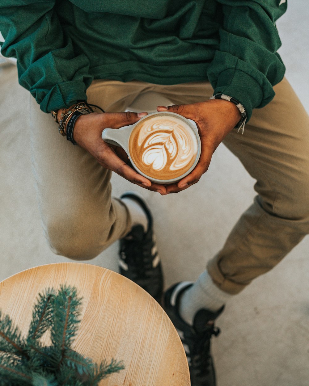 Persona sosteniendo taza con café diseñado