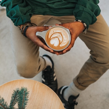 person holding cup with designed coffee