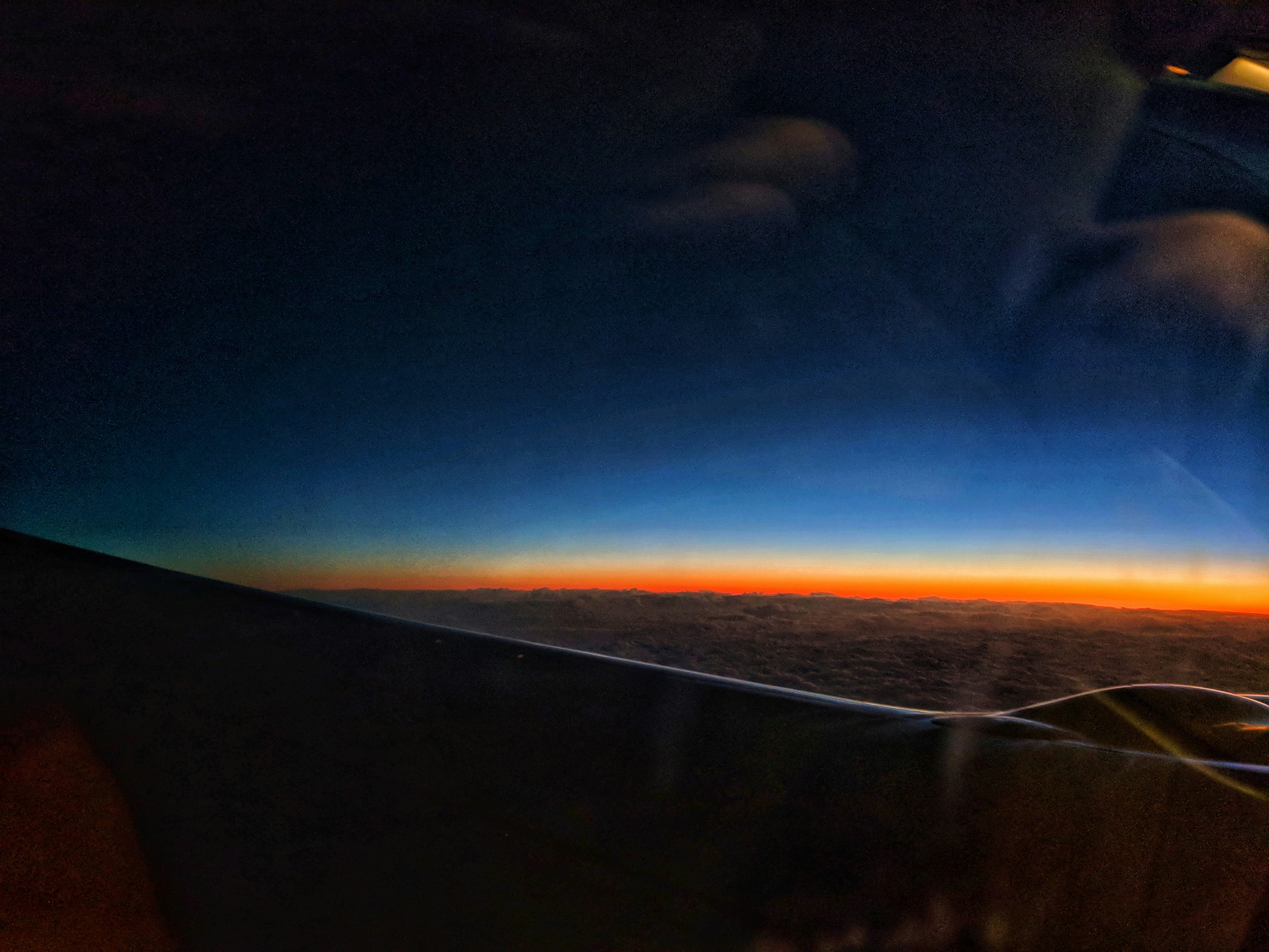 Airplane wing over clouds at sunset
