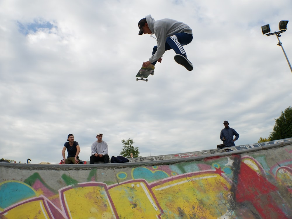 homme en l’air jouant à la planche à roulettes au-dessus de la rampe de planche à roulettes pendant la journée